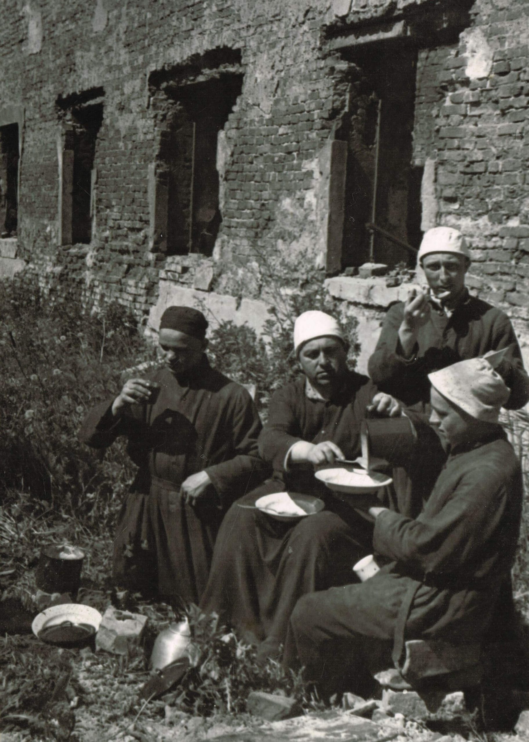 Bracia spożywają posiłek obok zrujnowanego szpitala, po II wojnie światowej